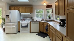 A kitchen with skylights, a refrigerator, stove, sink, and wooden cabinets. - Spacious house in serene peaceful setting 15 min from Lake Crescent&Crescent Bch (Port Angeles)