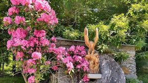 Ein Garten mit einem großen Felsen und einer Holzskulptur eines Adlers.