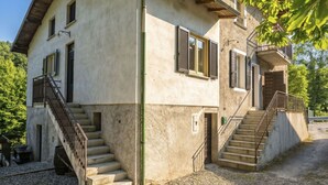 Ein zweistöckiges Gebäude mit einer Treppe zum oberen Stockwerk, einem Balkon und einem Fenster mit Fensterläden.