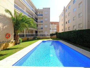 A swimming pool with a clear blue water surface, surrounded by a well-maintained lawn and a hedge. - Beautiful apartment for 5 guests with pool, A/C, TV, balcony and pets allowed (L'hospitalet De L'infant)