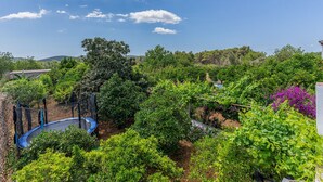A lush garden with various plants and a trampoline. - CAS CONSUL - Charming country house with private pool and free WiFi. (Sant Joan de Labritja)