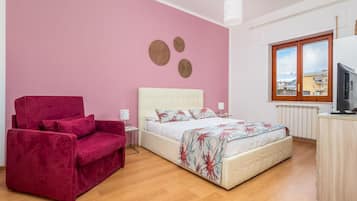 Una camera da letto con un letto, una sedia rossa, una finestra e un termosifone.
