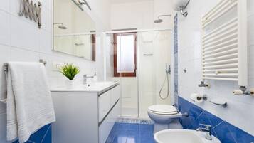 Un bagno moderno con doccia, WC, lavandino e uno specchio grande.
