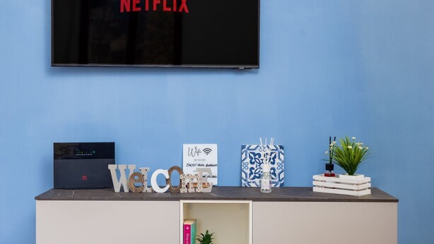 A room with a TV displaying 'NETFLIX,' a router, decorative items, and a plant on a shelf. - Smart Home Sorrento - City center (Sorrento)
