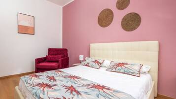Une chambre à coucher avec un lit, une chaise rouge et un mur rose.