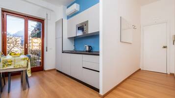 Una cucina compatta con forno a microonde, bollitore e zona pranzo con tavolo apparecchiato per due.