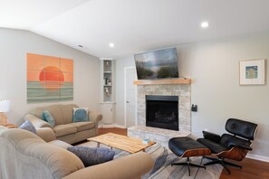 A living room with a fireplace, a sofa, a coffee table, and a TV.