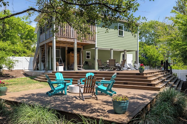 A two-story house with a porch, outdoor seating, and a small deck.