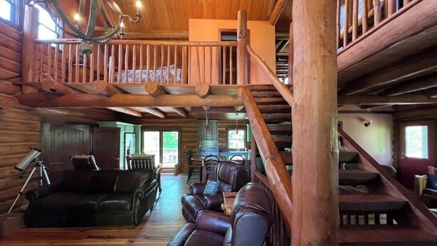 A log cabin interior with a wooden staircase, leather sofas, and a chandelier. - Cabin in the Vineyard. Very private! (Madison)