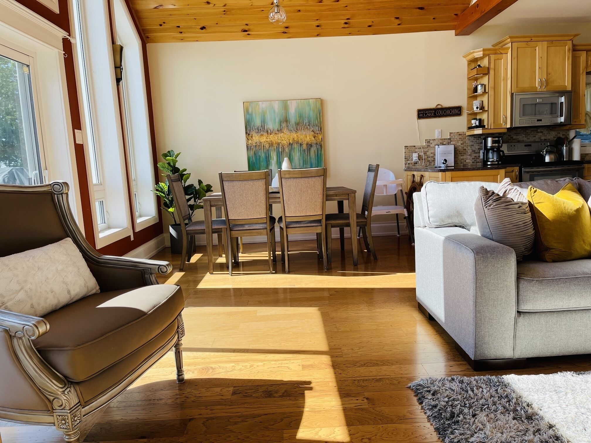 Ein geräumiger Wohnbereich mit Esstisch und Stühlen, einer Couch und einer Küche mit Holzschränken und modernen Geräten.