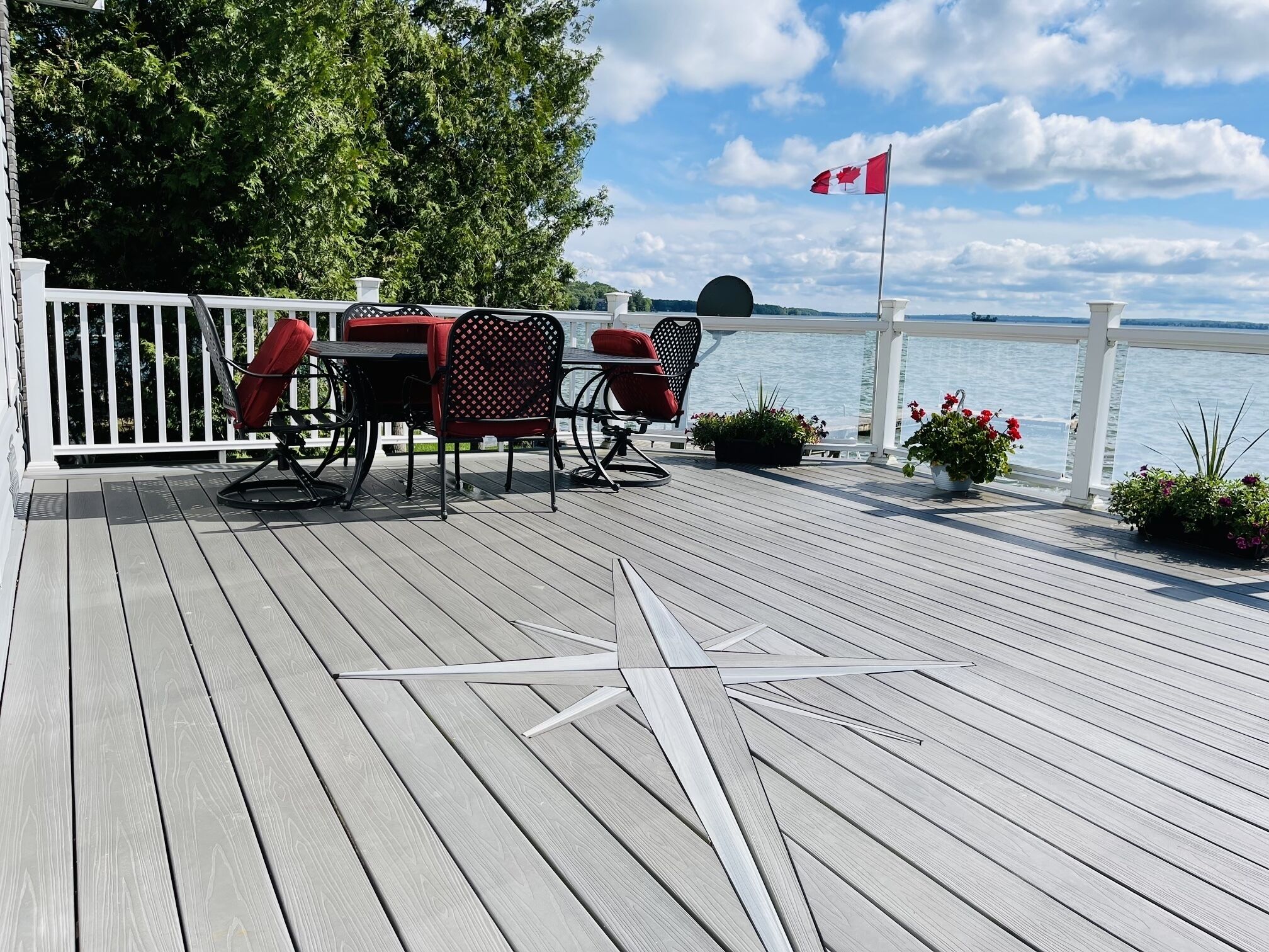 A wooden deck with a white railing, outdoor furniture, and a Canadian flag.