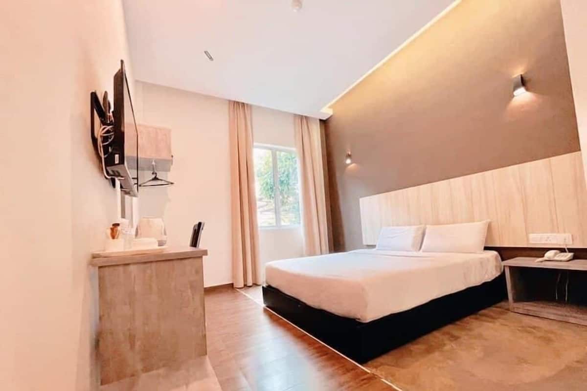 A modern hotel room with a large bed, a bedside table, a desk, and a mirror.