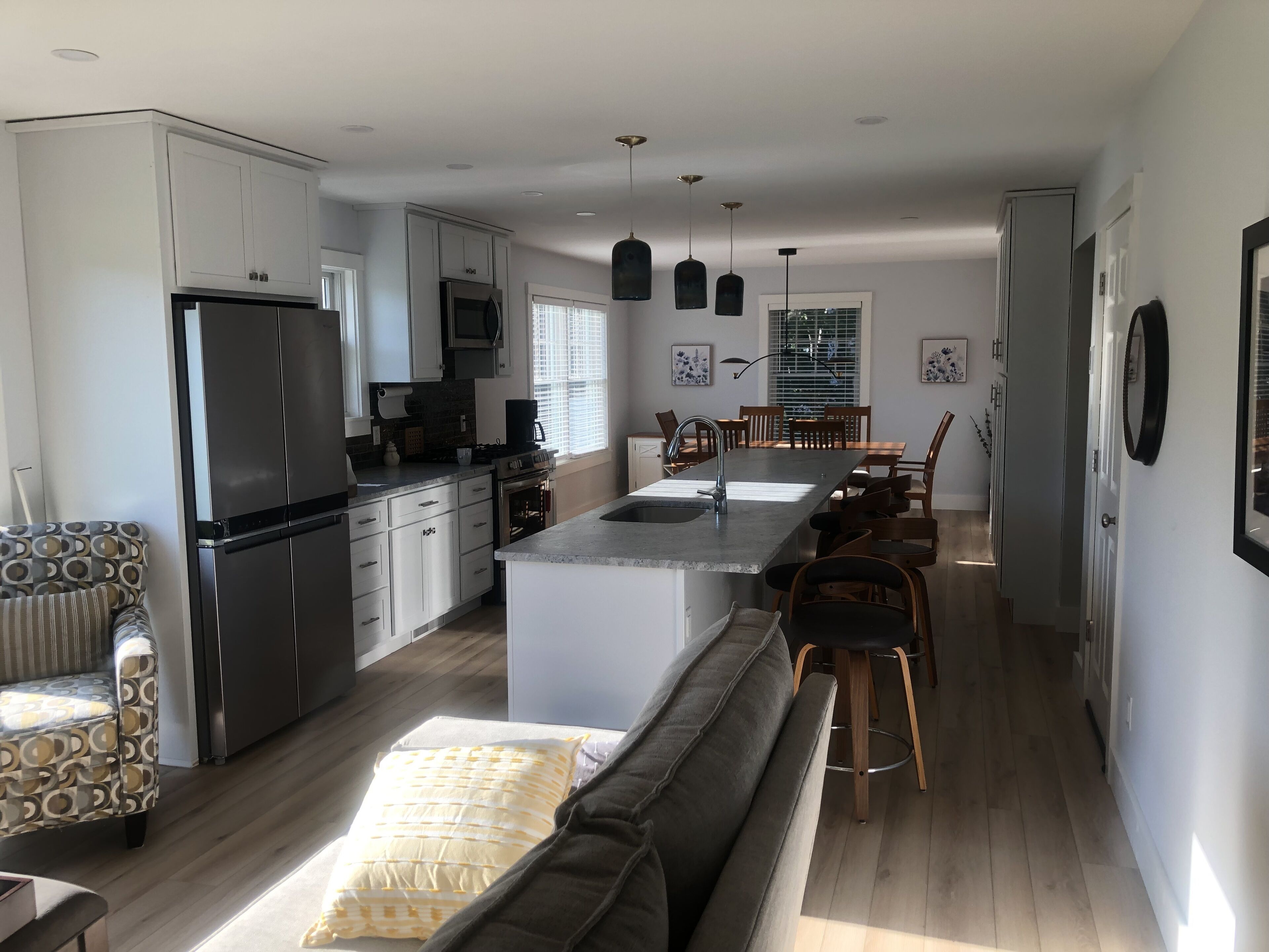 Une cuisine moderne avec des meubles blancs, un îlot central et des luminaires suspendus.