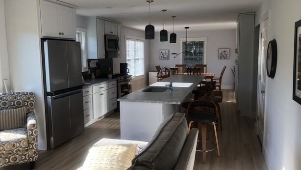 Una cocina moderna con armarios blancos, una isla central e iluminación colgante.