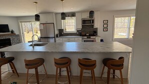 Una cocina moderna con una isla grande, taburetes de bar y un comedor.