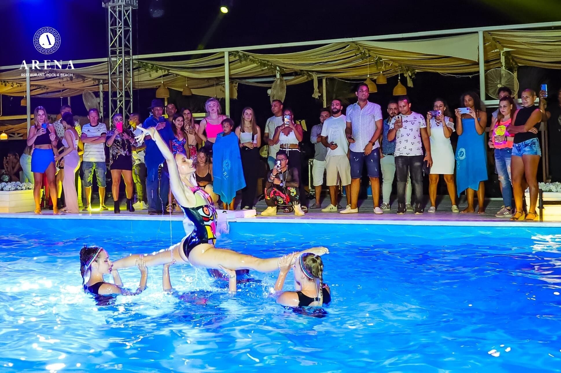 Une piscine où un groupe de personnes regarde un spectacle.