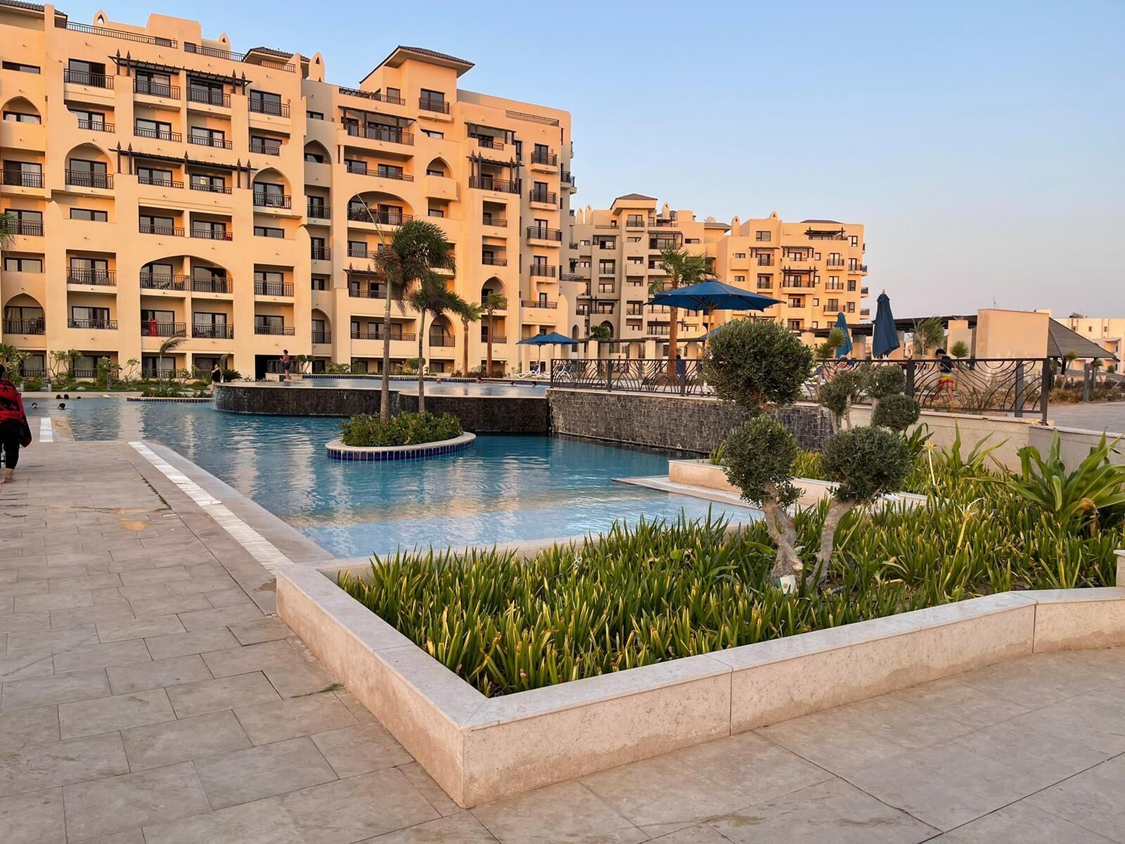 Un hotel con varios balcones, piscina y un jardín ajardinado.