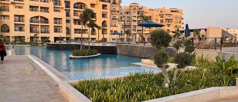 Un hotel con varios balcones, piscina y un jardín ajardinado.