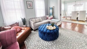 Una sala de estar con sofá, reposapiés y sillas.