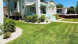 Una casa de dos pisos con porche delantero, piscina y césped bien cuidado.