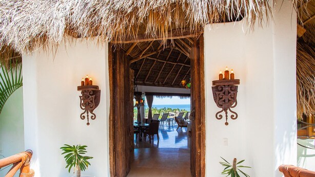 A thatched-roof entrance with two wall-mounted sconces and potted plants. - Ocean views, breathtaking sunsets, gorgeous villa (Sayulita)