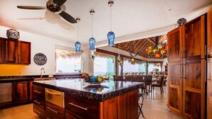 A spacious kitchen with a large island, wooden cabinets, and a dining area with a view. - Ocean views, breathtaking sunsets, gorgeous villa (Sayulita)