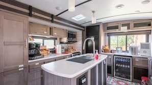 A compact kitchen with modern appliances, a central island, and a refrigerator.