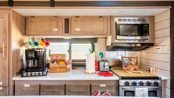 Cocina compacta para autocaravana con cafetera, microondas y estufa.