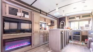 A modern RV kitchen with a built-in fireplace, a microwave, and a refrigerator.