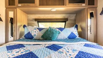 A bedroom with a bed, pillows, and a window.
