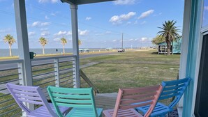 Une terrasse couverte, agrémentée de chaises colorées, d’où l’on peut admirer la plage et l’océan.