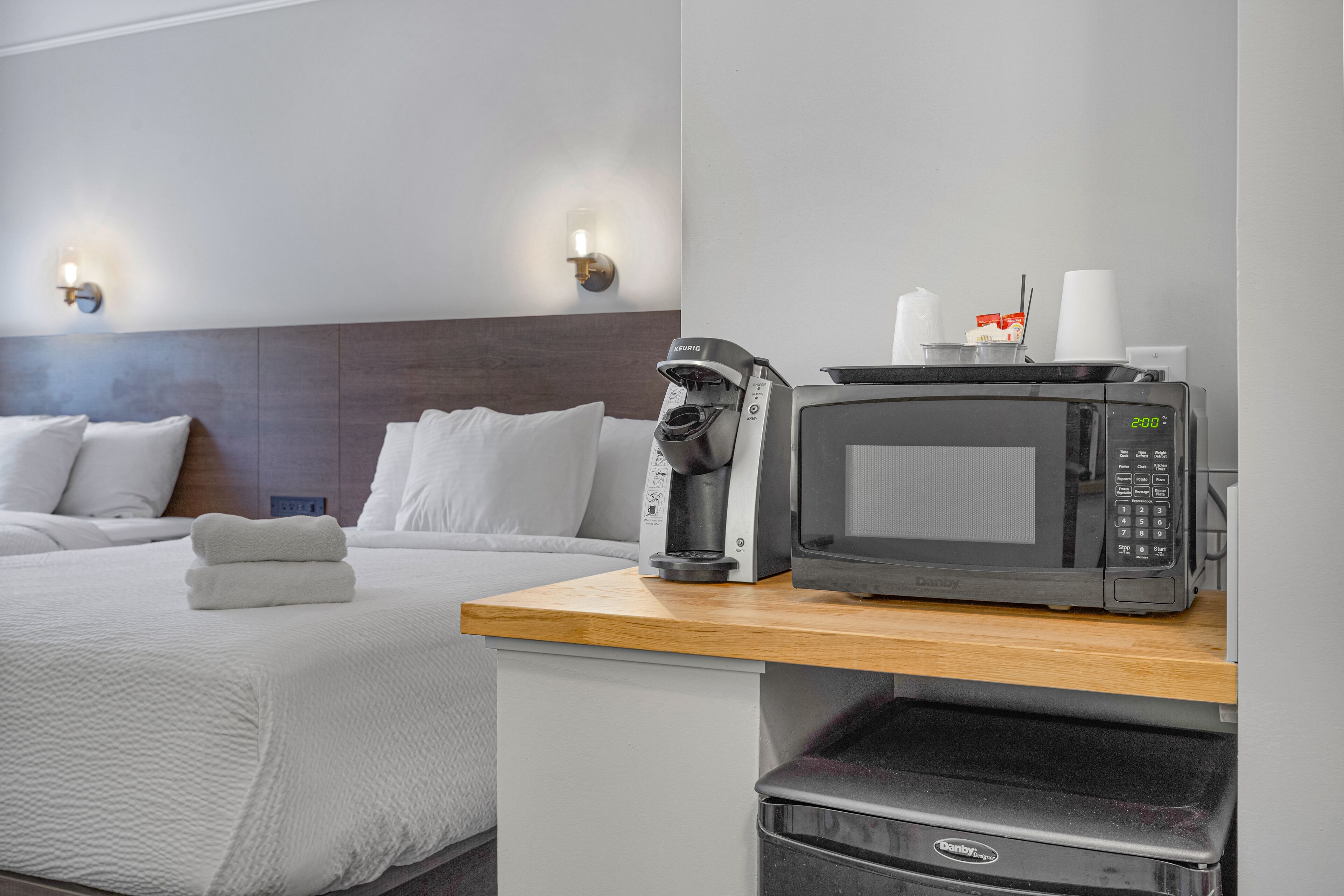 Une chambre d’hôtel équipée d’un lit, d’un four à micro-ondes, d’une machine à café et d’une poubelle.