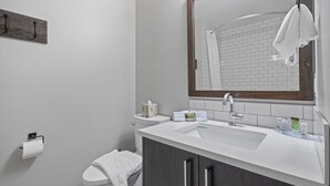 A modern bathroom with a white sink, a large mirror, and a toilet.