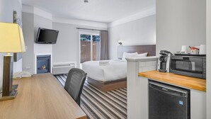 Ein Hotelzimmer mit einem Bett, einem Schreibtisch, einem Sessel, einem Fernseher, einer Kaffeemaschine und einer Mikrowelle.