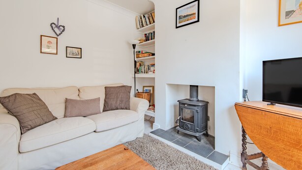 A living room with a white sofa, a fireplace, a bookshelf, and a television.