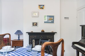 Un comedor con mantel a cuadros, un piano y una chimenea.
