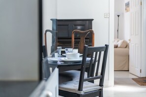 Un comedor con una mesa dispuesta para dos personas, una silla de madera oscura y un aparador blanco al fondo.