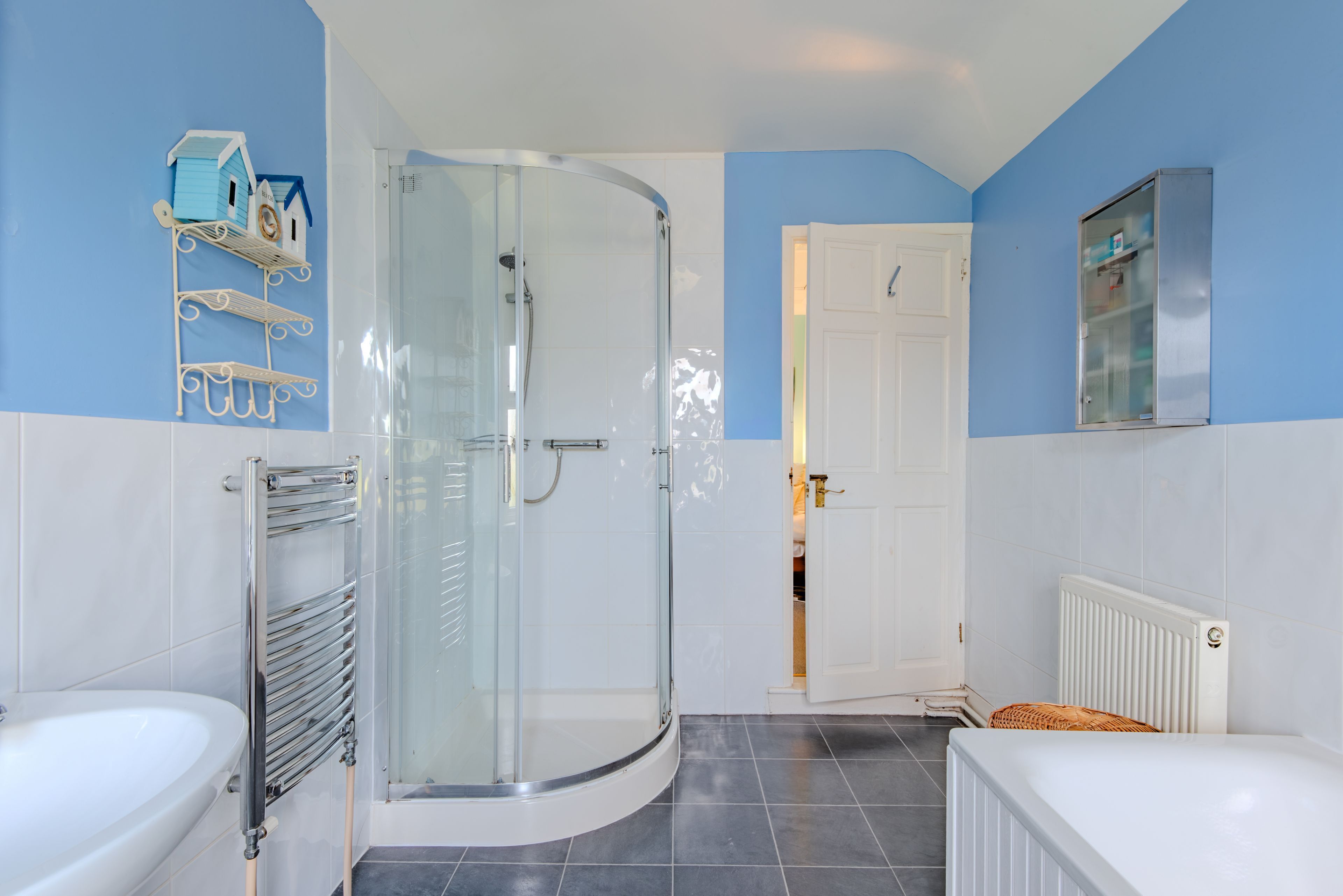 A bathroom with a glass shower enclosure, a white bathtub, and a white toilet.