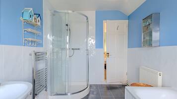 A bathroom with a glass shower enclosure, a white bathtub, and a white toilet.