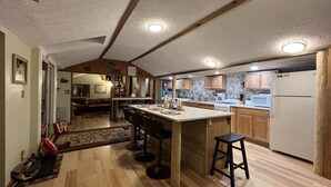 A spacious kitchen with wooden cabinets, a central island with stools, and a refrigerator.