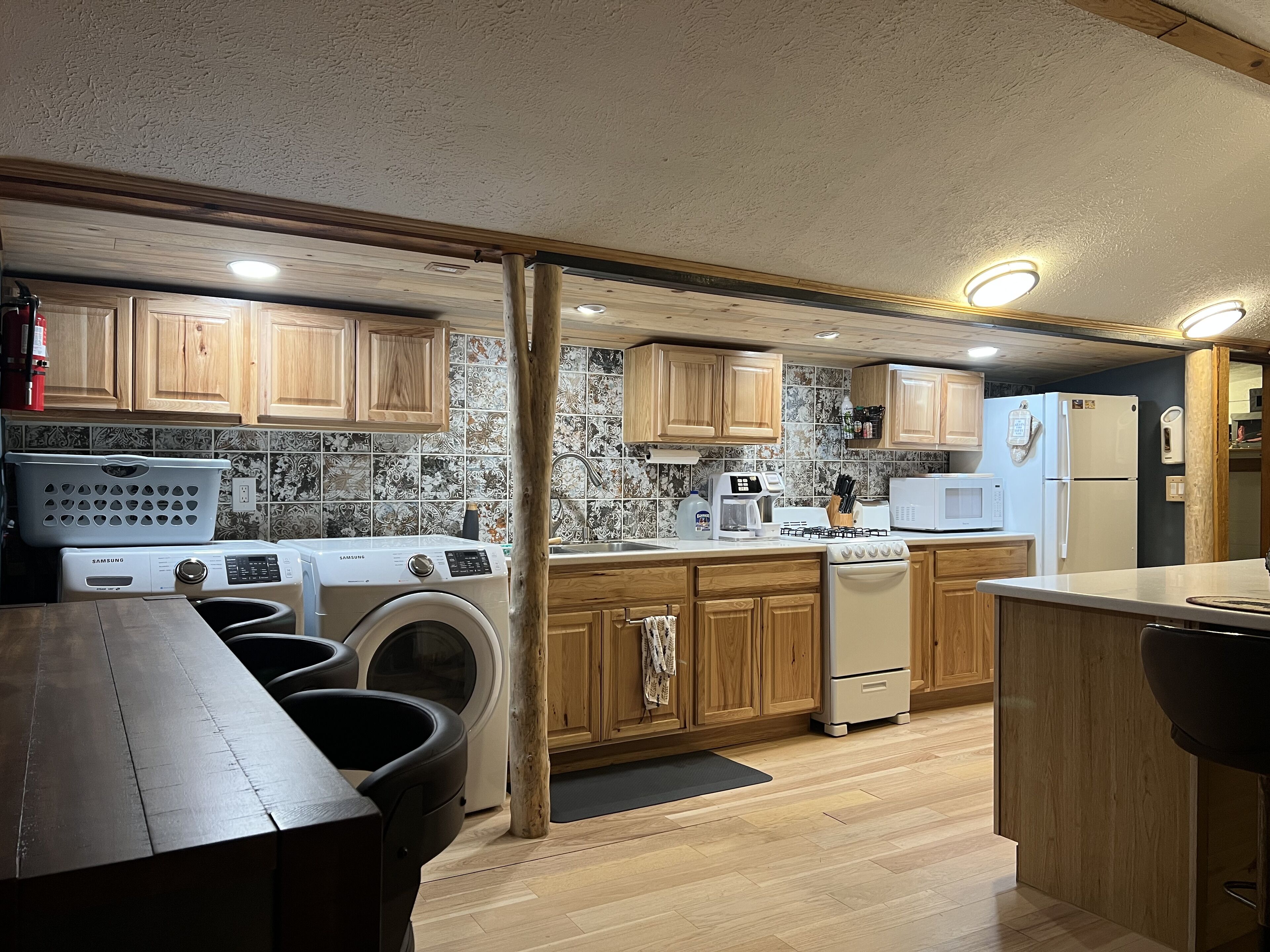 A compact kitchen with wooden cabinets, a washing machine, a microwave, and a refrigerator.