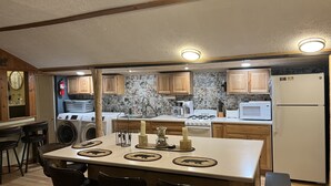 A compact kitchen with wooden cabinets, a built-in washing machine, a gas stove, and a refrigerator.