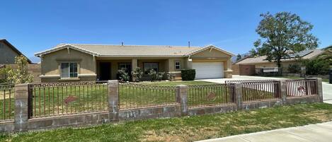 A residential house with a garage, a fenced yard, and a well-maintained lawn.