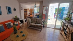 Una sala de estar con sofá, sillón, mesa de centro y un comedor con mesa y sillas.