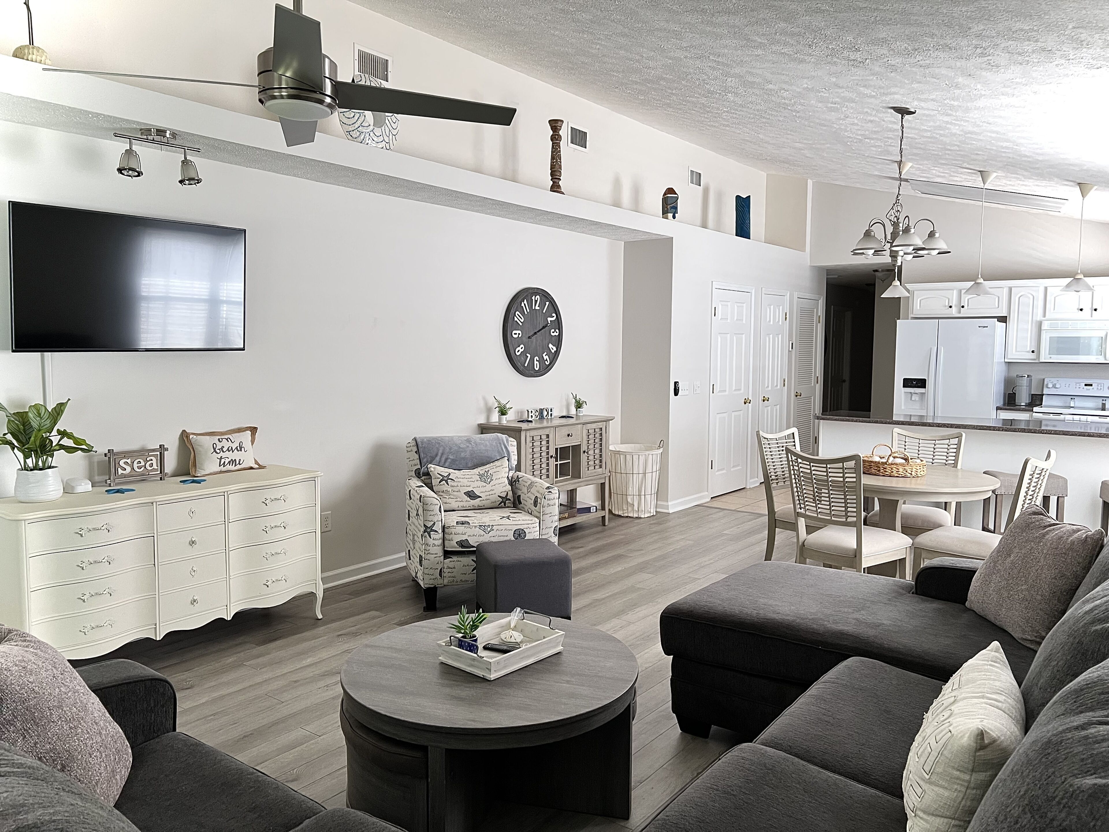 Ein modernes Wohnzimmer mit Flachbildfernseher, rundem Couchtisch und einer gemütlichen Sitzecke.