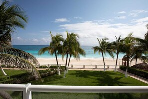 A beach view with palm trees and a white fence. - Nizuc Villas – Beachfront villa with 3 bedrooms and 4 bathrooms • Swimming Pool – Gym – Ocean View (Cancún)
