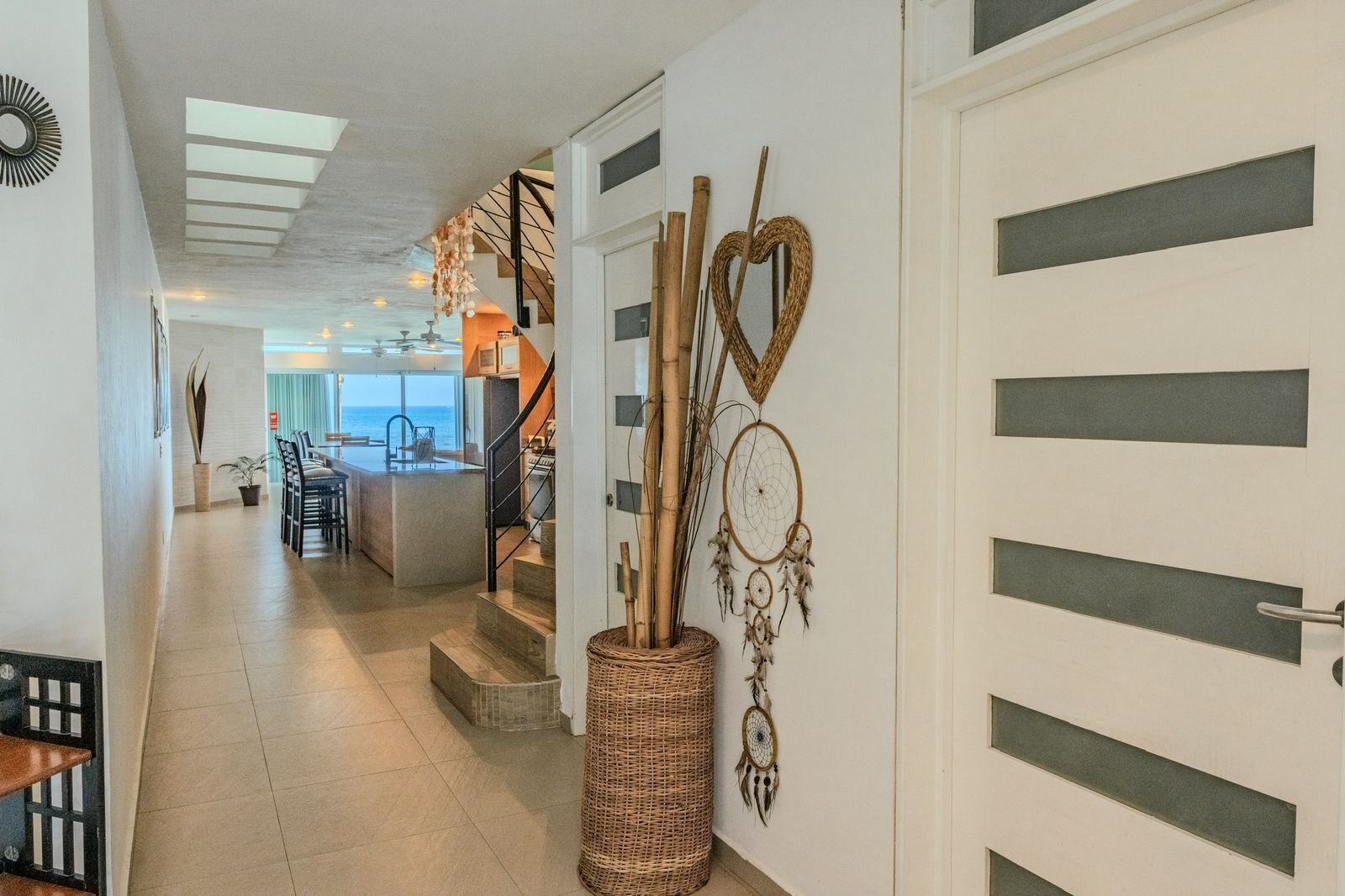 A modern interior with a kitchen, dining area, and a staircase leading to an upper level.