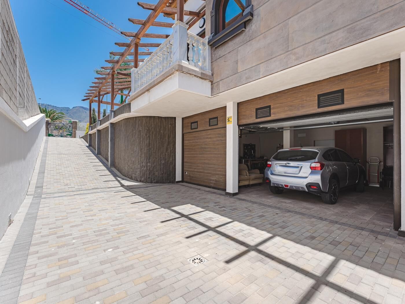 Een modern gebouw met een garage, een overdekt terras en uitzicht op de bergen.