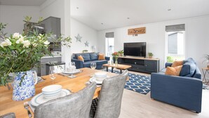 Een moderne woonkamer met een eethoek, een televisie en een open haard.