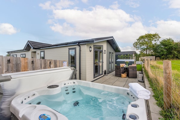Une maison moderne dotée d’un jacuzzi, d’un espace salon extérieur et d’une cour clôturée.